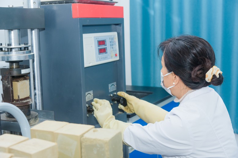 Laboratory technician operating compression testing machine