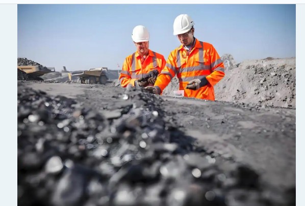 Workers in hard hats inspecting material at a mining site